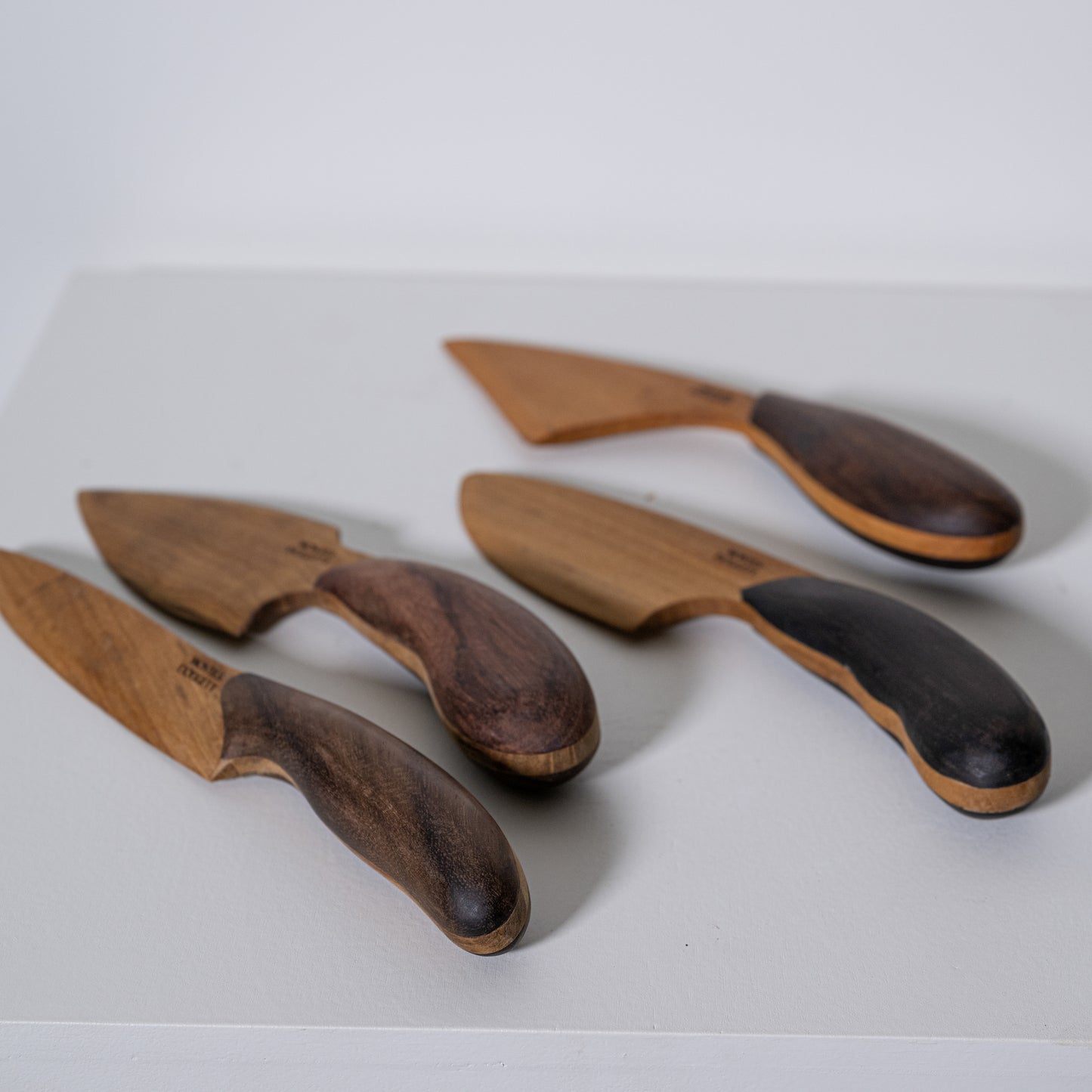 Set of four teak and sono kitchen knives with dark polished wooden handles and light-toned blades
